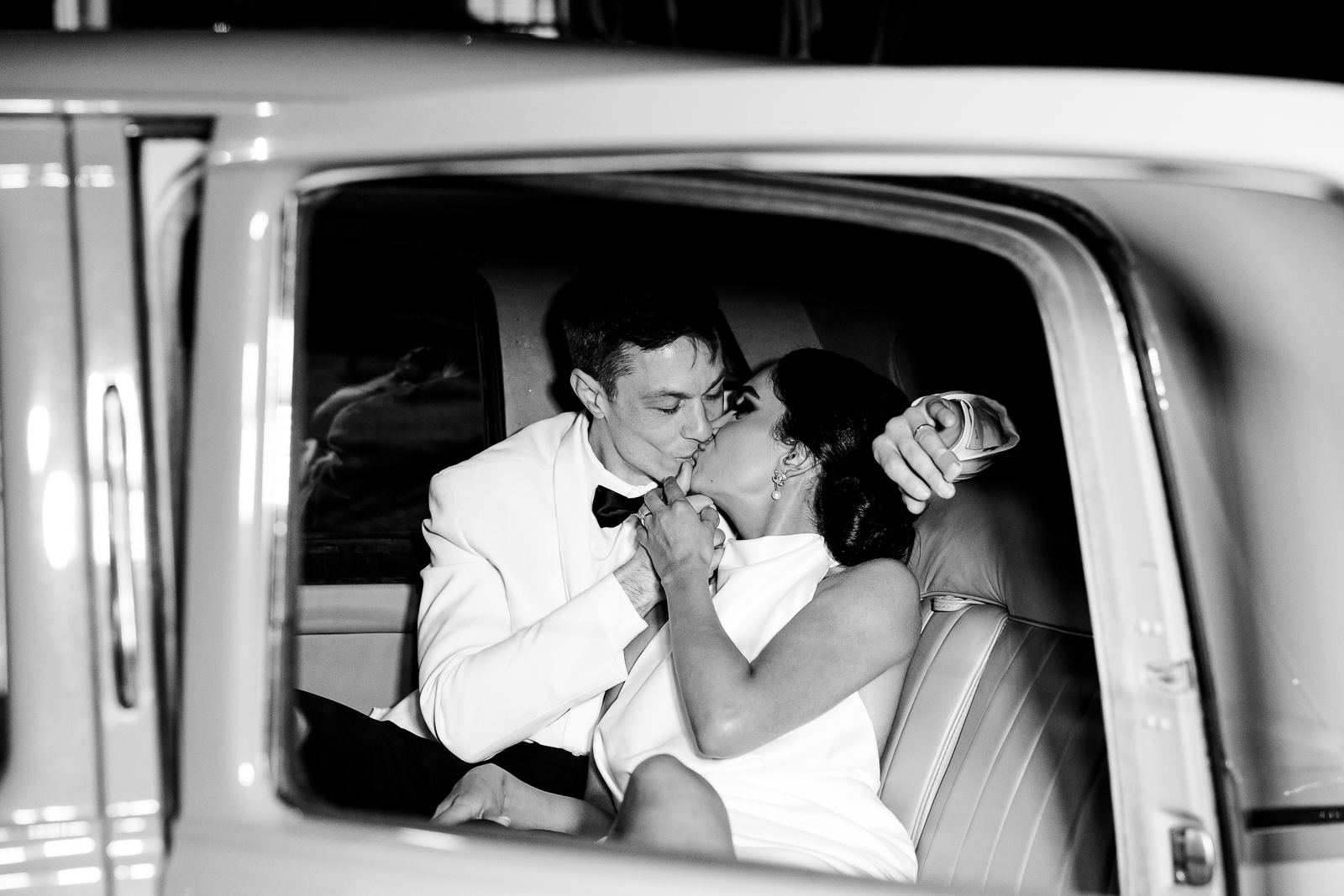 Bride & groom kiss in the back seat of a Bentley car
