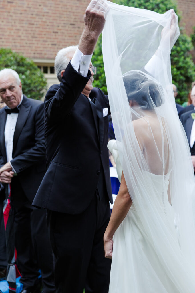 Father lifting bride's veil over her head